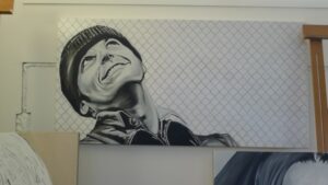 Portrait painting of a man in a knit cap with a knowing grin, by Kim Parrent
